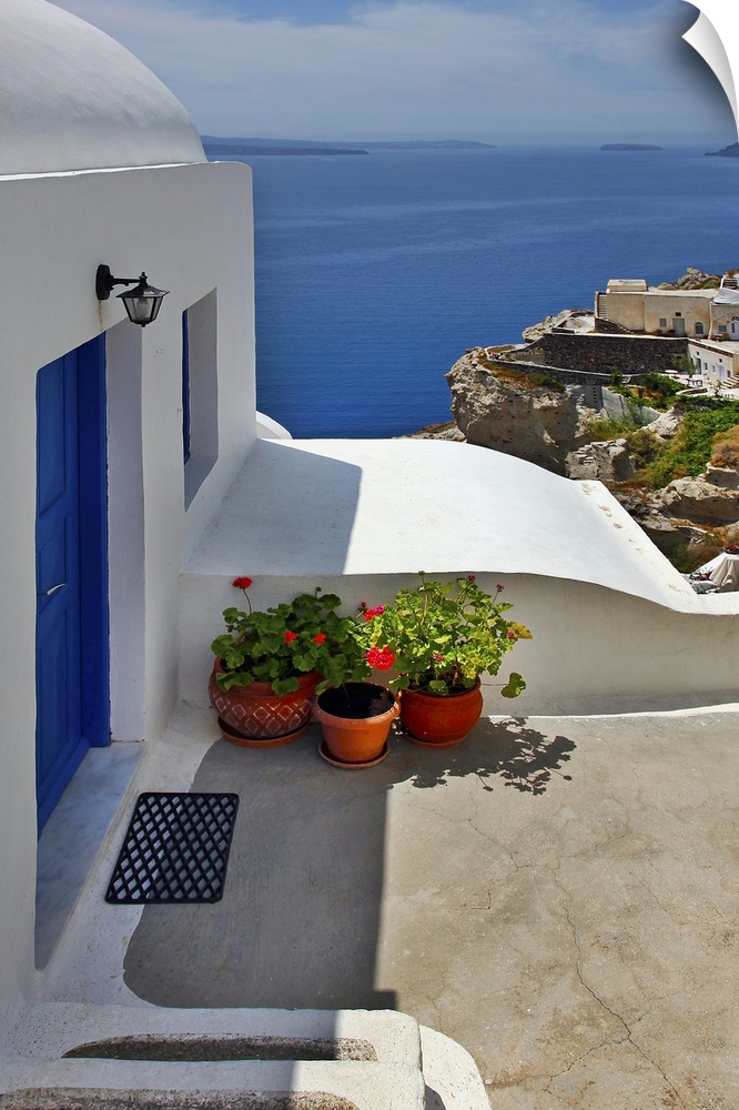 Vertical photo of home with blue door and ocean view in the village of Oia on the island of Santorini, Greece