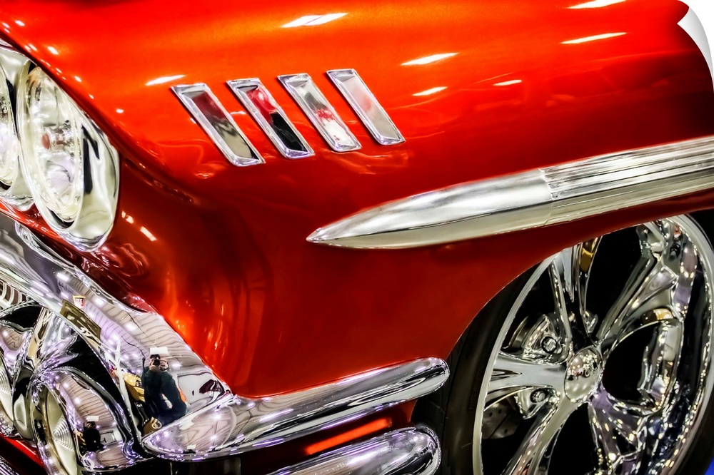 Headlight and wheel rim detail of a bright red muscle car.