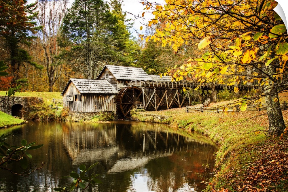 An old wooden watermill in a forest in the fall.