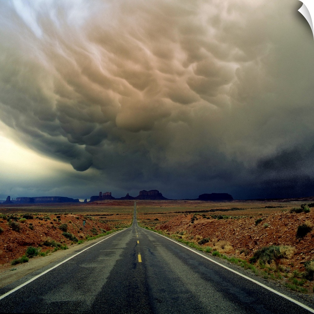 Heavy storm clouds over a road through the desert in Monument Valley.