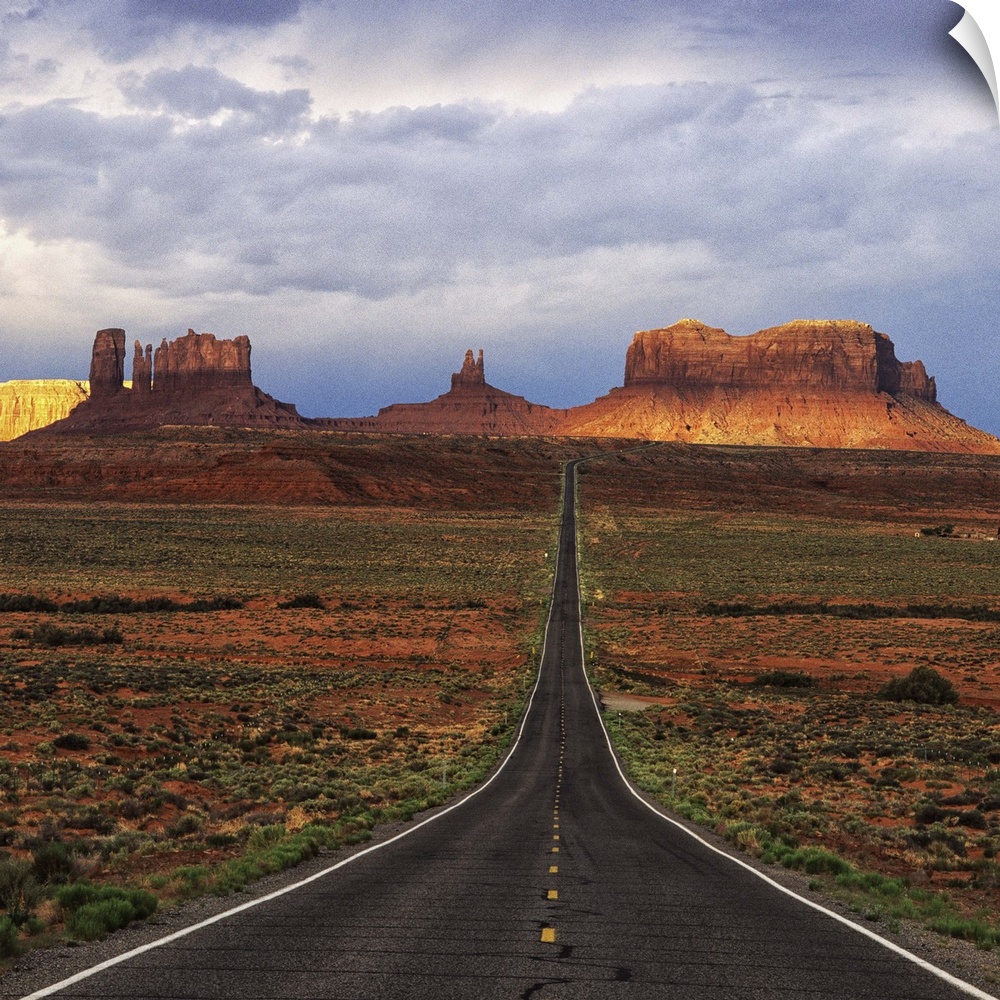 A road leading towards the tall rock formations in Monument Valley, Arizona.