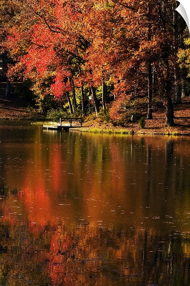 Vertical photo on canvas of a lake with a dock and fall foliage surrounding it.