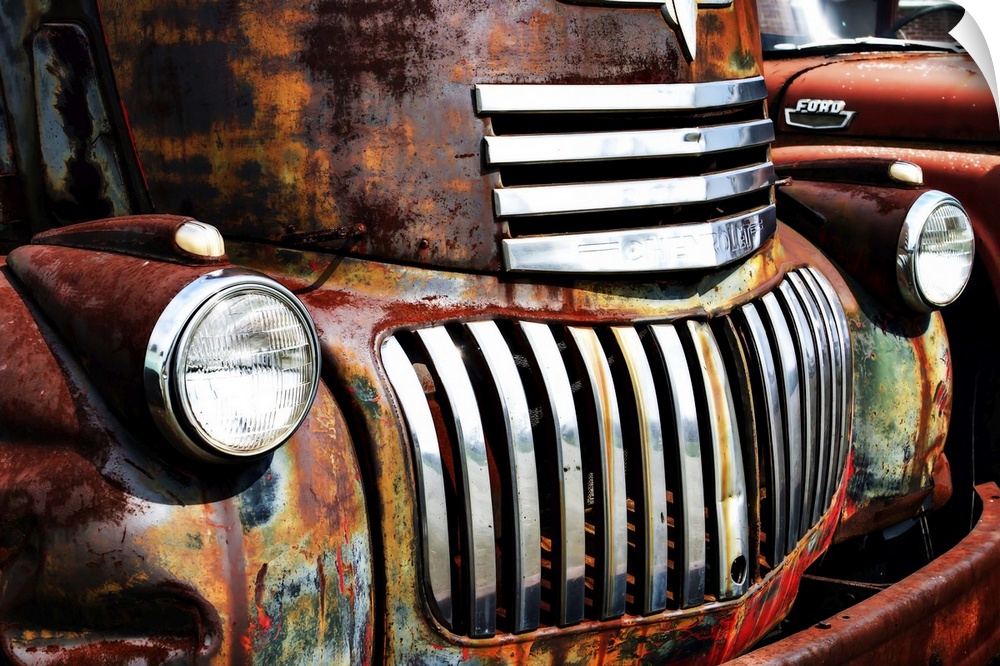 Close-up photograph of the headlights and grill of an old and rusty truck.