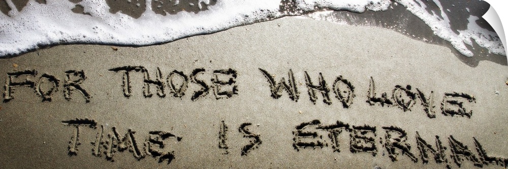 A Bible verse drawn in the sand near the ocean water.