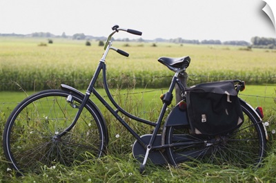 a bike resting along a fence in the countryside