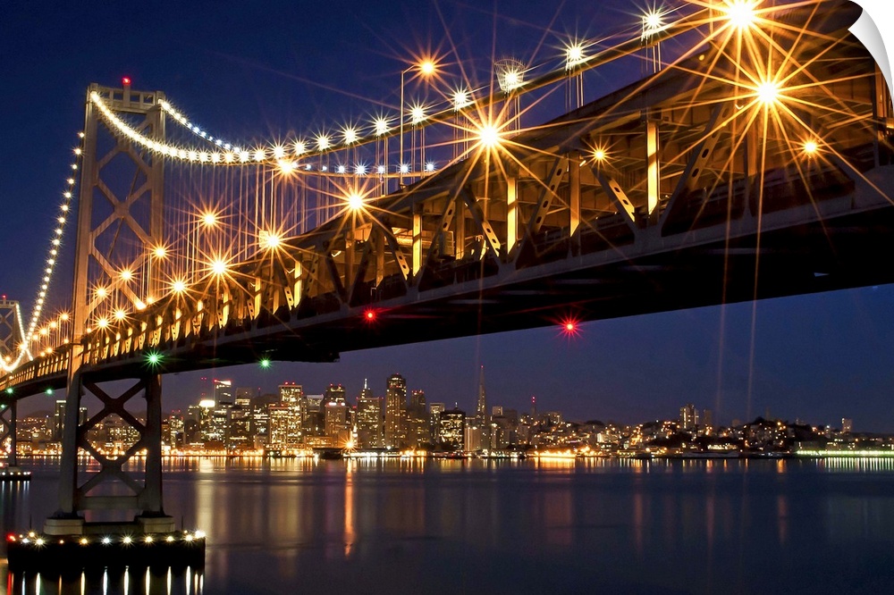 A burst of lights on the Bay Bridge and San Francisco skyline in the background.