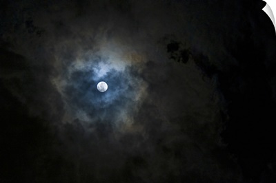 A full moon shining through a break in the clouds