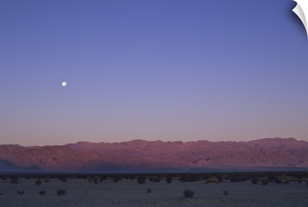 A moon above a mountain range in Death Valley National Park.