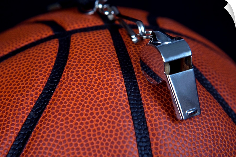 A referee's whistle rests on top of a basketball.  Shot with Canon 5D Mark II.