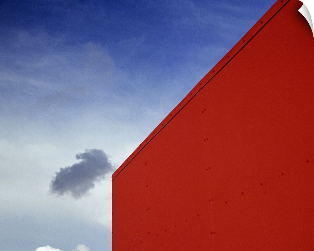 A shadowed cloud floating through blue sky over the red corner of James John School.