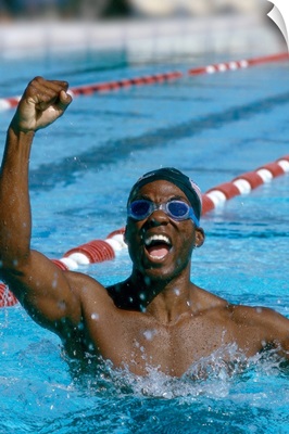 A young male swimmer raising his hands in victory