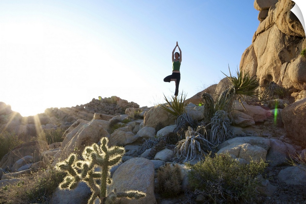 A young woman practices yoga on a rock outdoors in California.