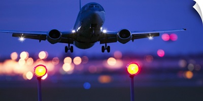 an airplane landing with blurred lights of the airport in the background