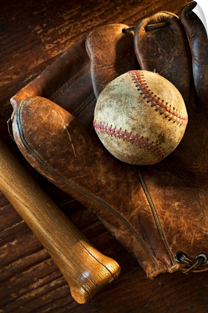 Wall docor of a worn baseball laying on top of an old baseball mit with a wooden bat next to it.