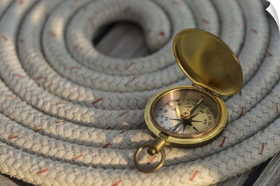 Antique compass on coiled rope on sailboat