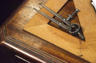 Antique set square and pair of compasses on wooden table