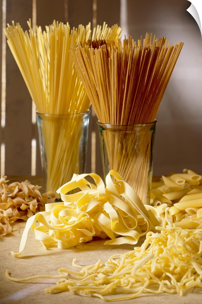 Dry pasta in glass jars and fresh pasta scattered in front of it is photographed artistically.