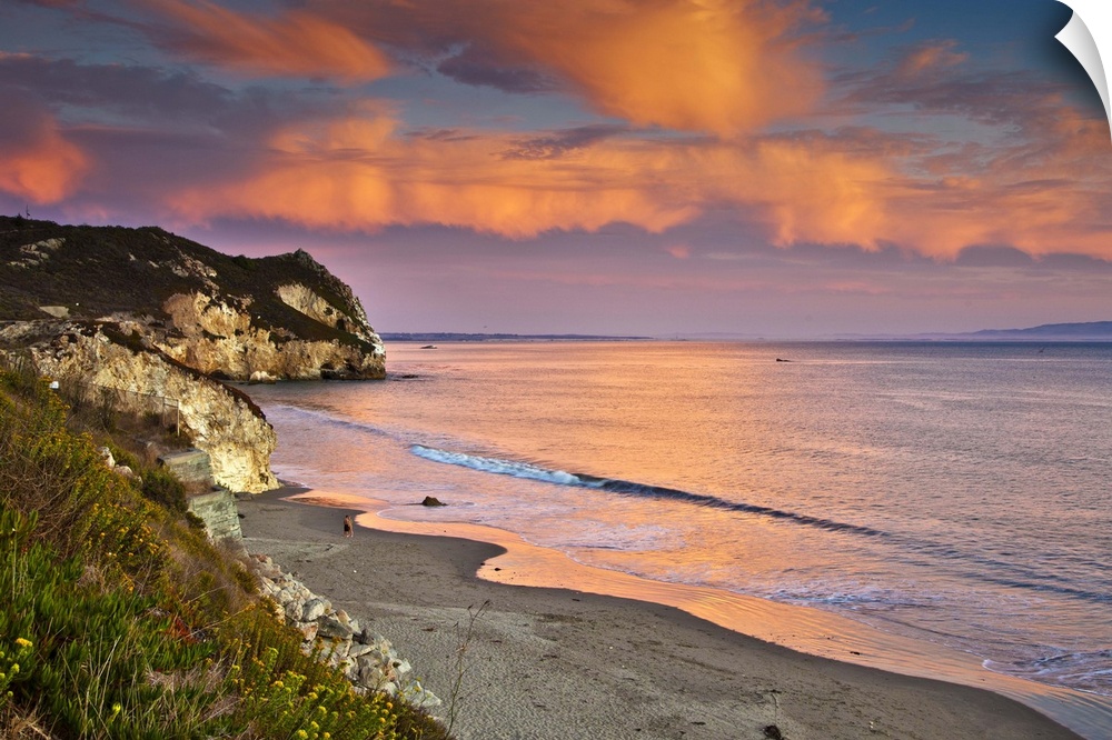 Horizontal photograph on a big wall hanging of the rocky coast line along Avila Beach in California, beneath the setting s...