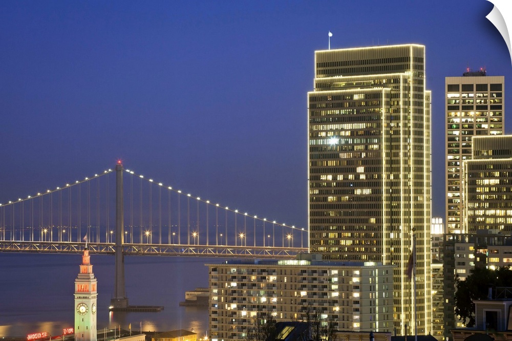 Holiday lights are on downtown buildings, bay bridge and Ferry building in San Francisco.