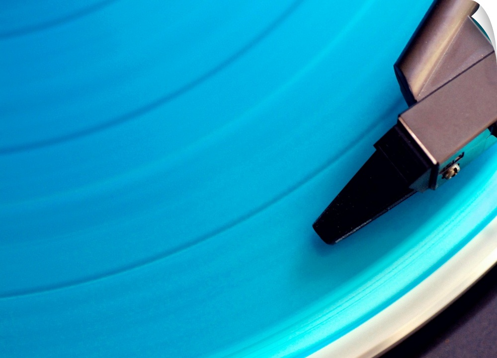 Blue vinyl playing on the turn table. View of needle on record.