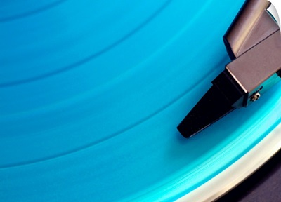 Blue vinyl playing on the turn table. View of needle on record.