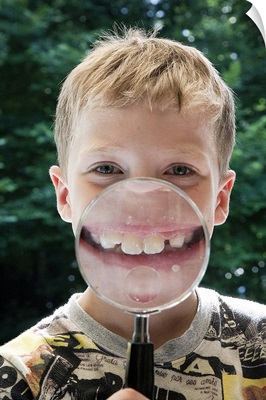 Boy behind magnifying glass smiling