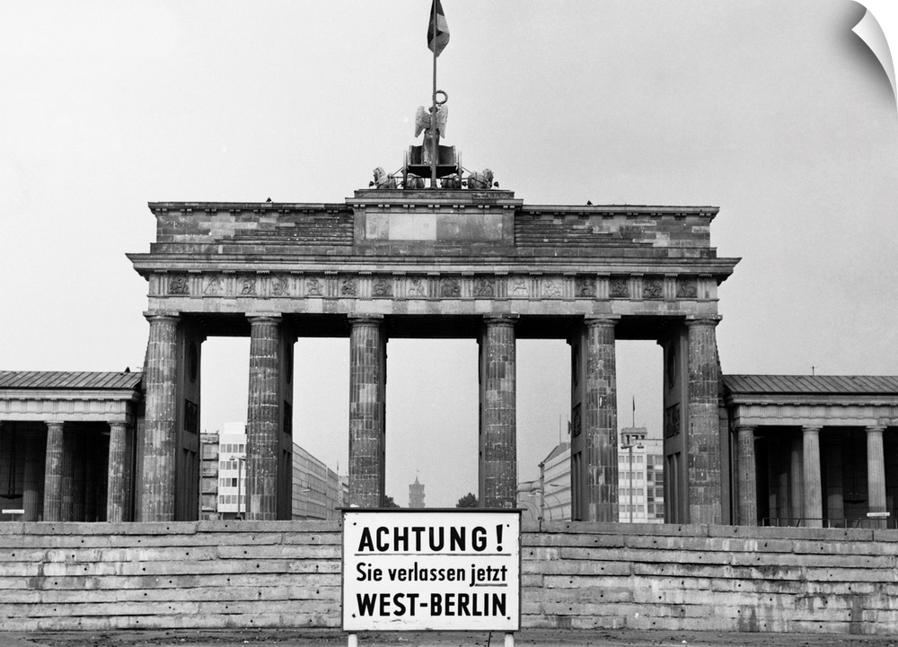 The Brandenburg Gate in East Berlin. In front, a sign in German warns of the impending border between East and West Berlin...