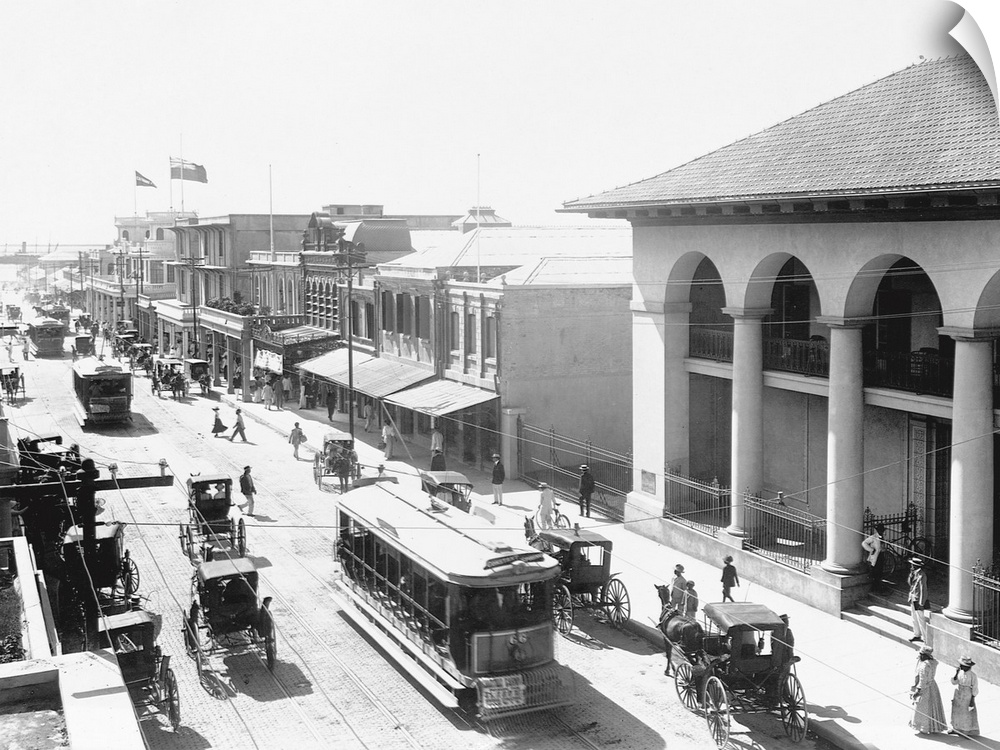 Carriages, trolleys, and pedestrians crowd a busy street in Kingston, Jamaica.