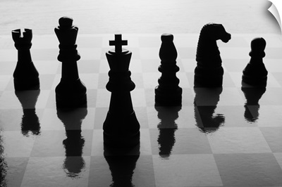 Chess pieces on chess board in black and white silhouette.