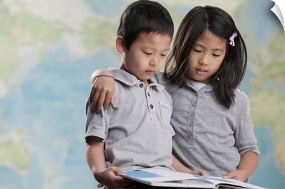 Children reading book near map