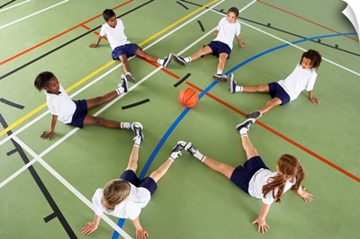 Children sitting on the floor of a sports hall with a basketball
