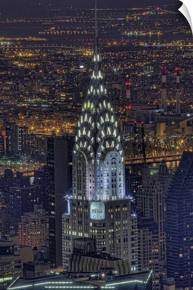 Aerial vertical picture of the top of the Chrysler building lit up at night with the rest of downtown New York lit up in t...