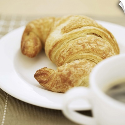 close-up of a cup of hot black coffee and a croissant