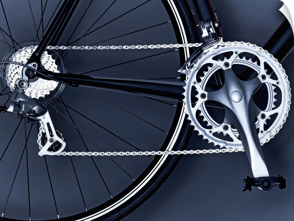 Oversized, horizontal, close up photograph of part of the back wheel, the chain, gears and pedal of a black bicycle.