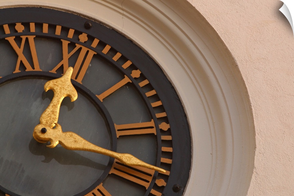 Landscape, large, close up photograph of a partial clock on a tower.  The large golden hands of the round clock are sittin...