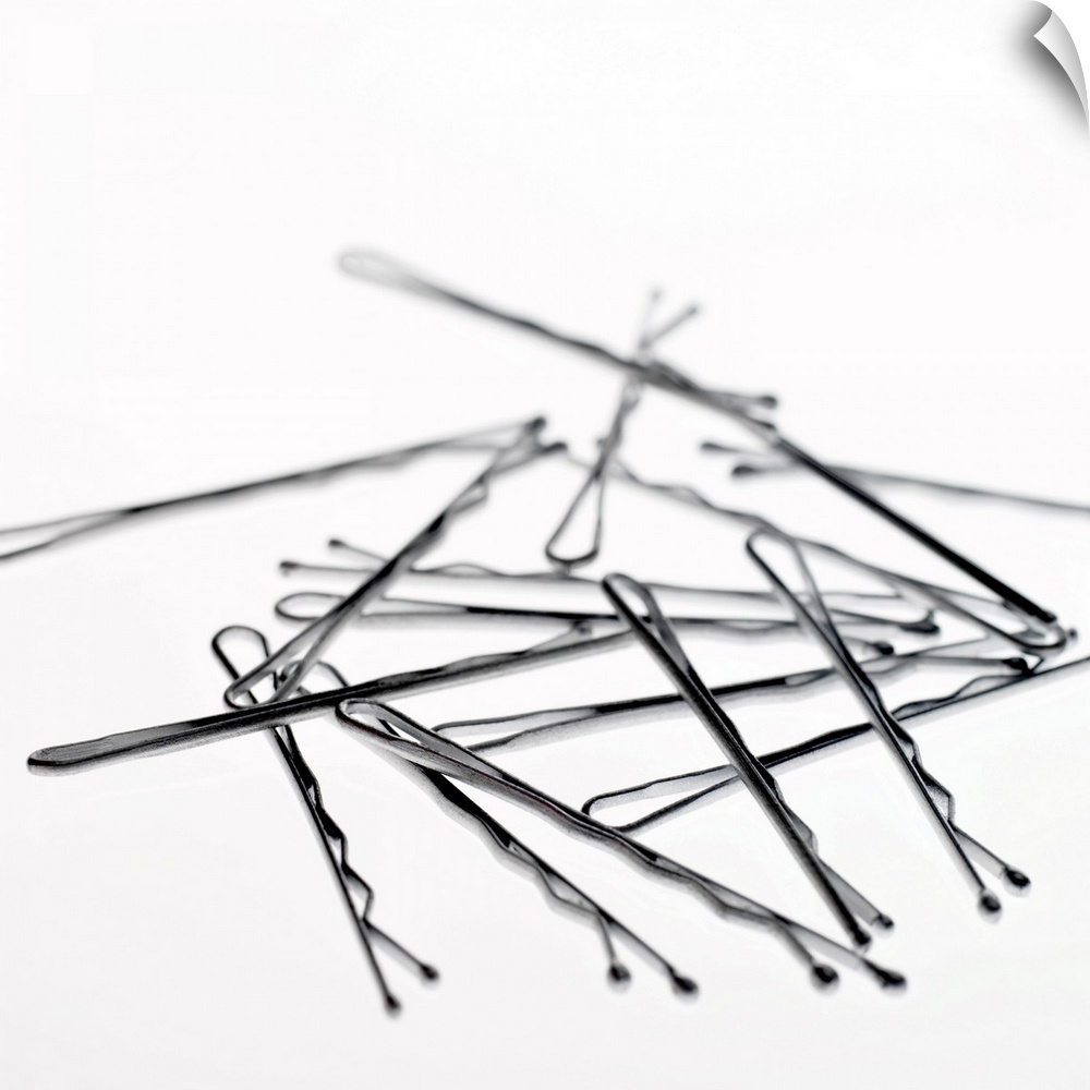 Square, large close up photograph of a small pile of hair pins or bobby pins, on a plain white background.