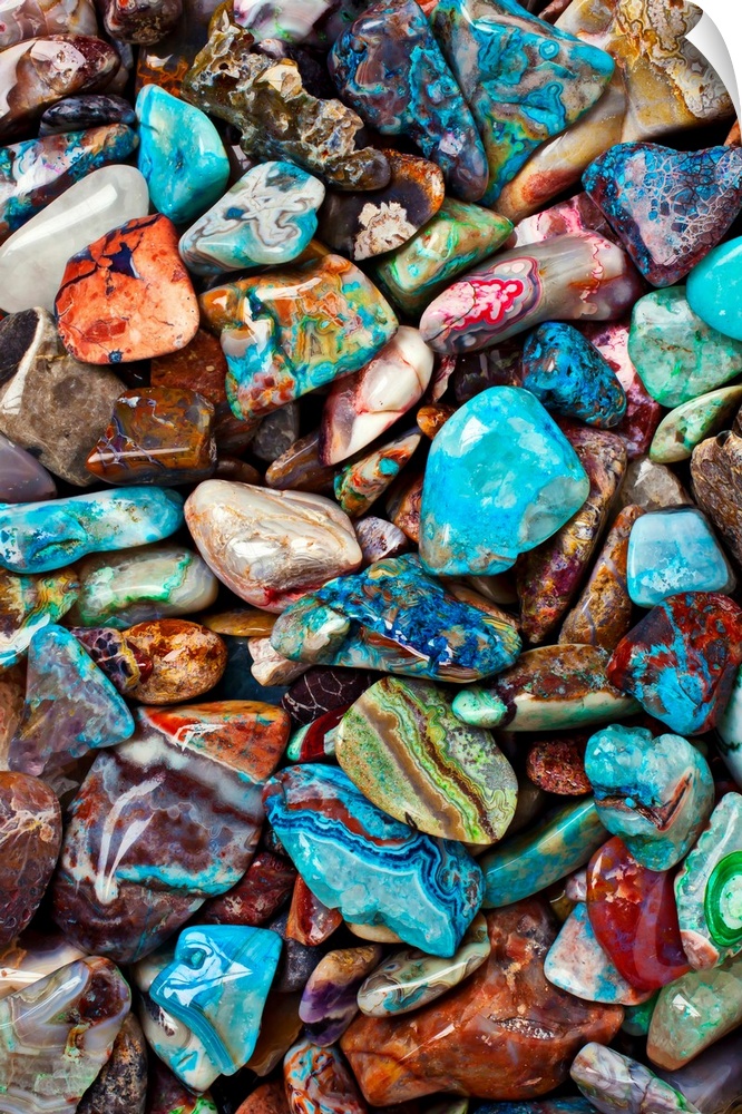 Large close-up photograph focuses on an abundance of vibrantly tinted smooth rocks as they sit next to and on top of each ...