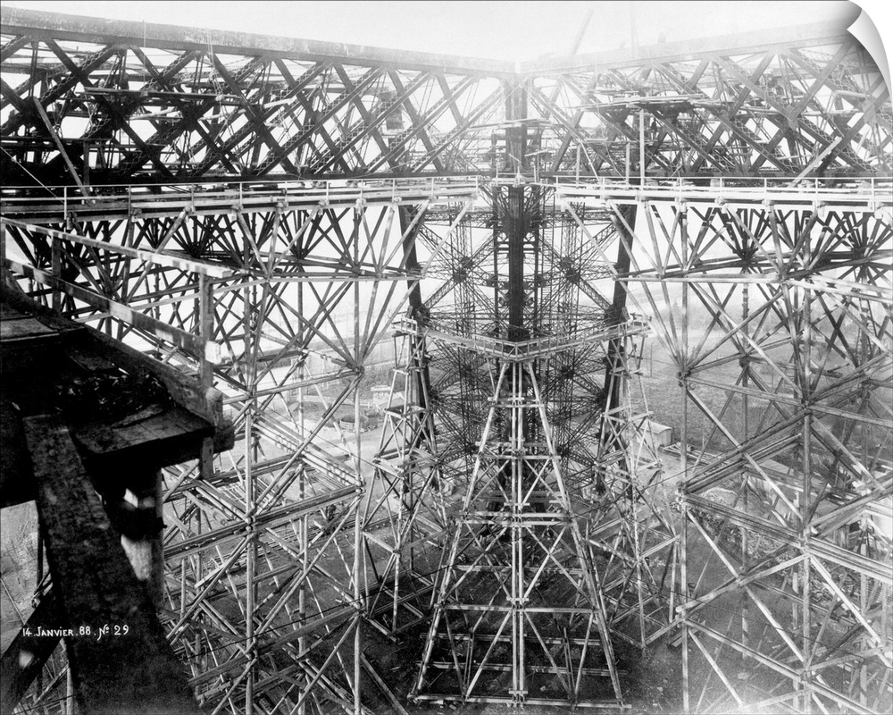 Eiffel Tower under construction. Intricate mass of ironwork at the level of the first platform with temporary supporting s...