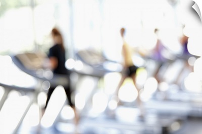 Defocused view of people on treadmills in health club