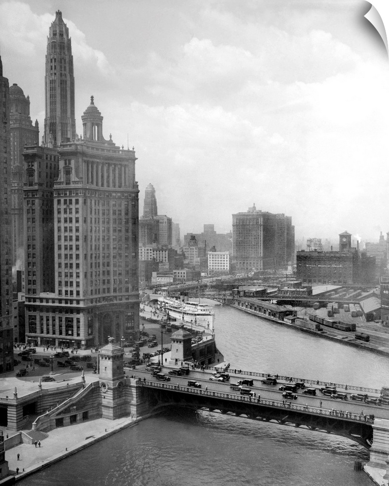 1920s high angle view looking west above the Chicago River with Michigan Ave. bridge in the foreground. Wacker Drive winds...