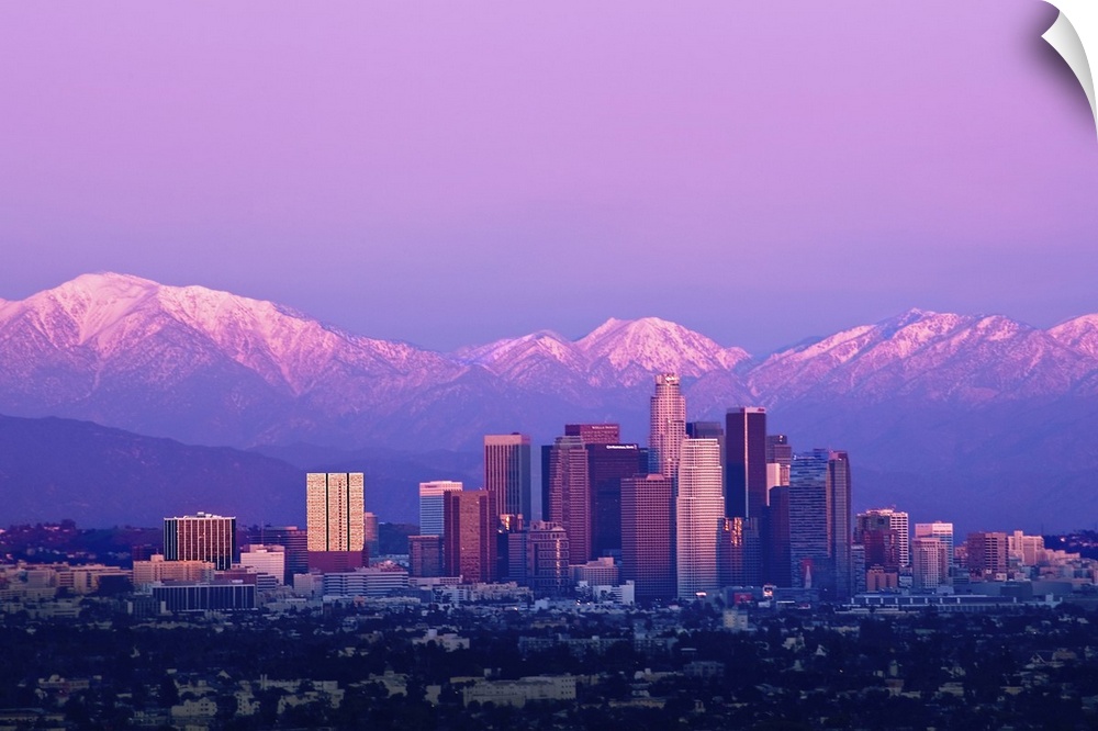 Downtown Los Angeles and sunset. Buildings are lit from setting sun and mountains are capped with snow in distance. Tones ...
