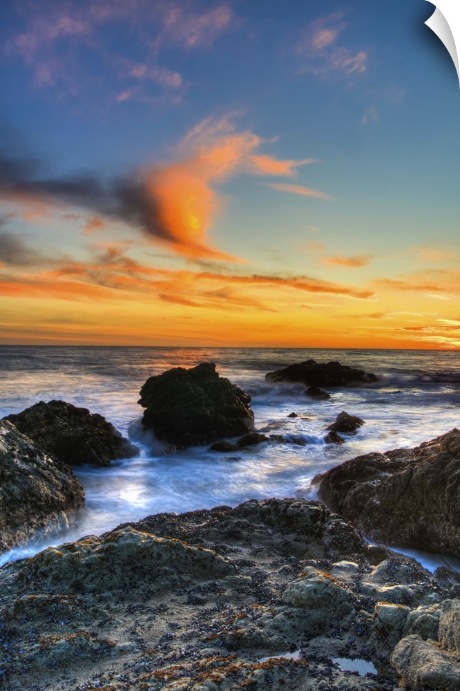Dramatic sunset on rocky beach in Malibu, California.
