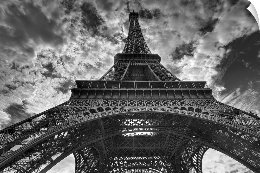 Landscape, low angle photograph looking up one side of the Eiffel Tower, the background is a sky full of small, fluffy clo...