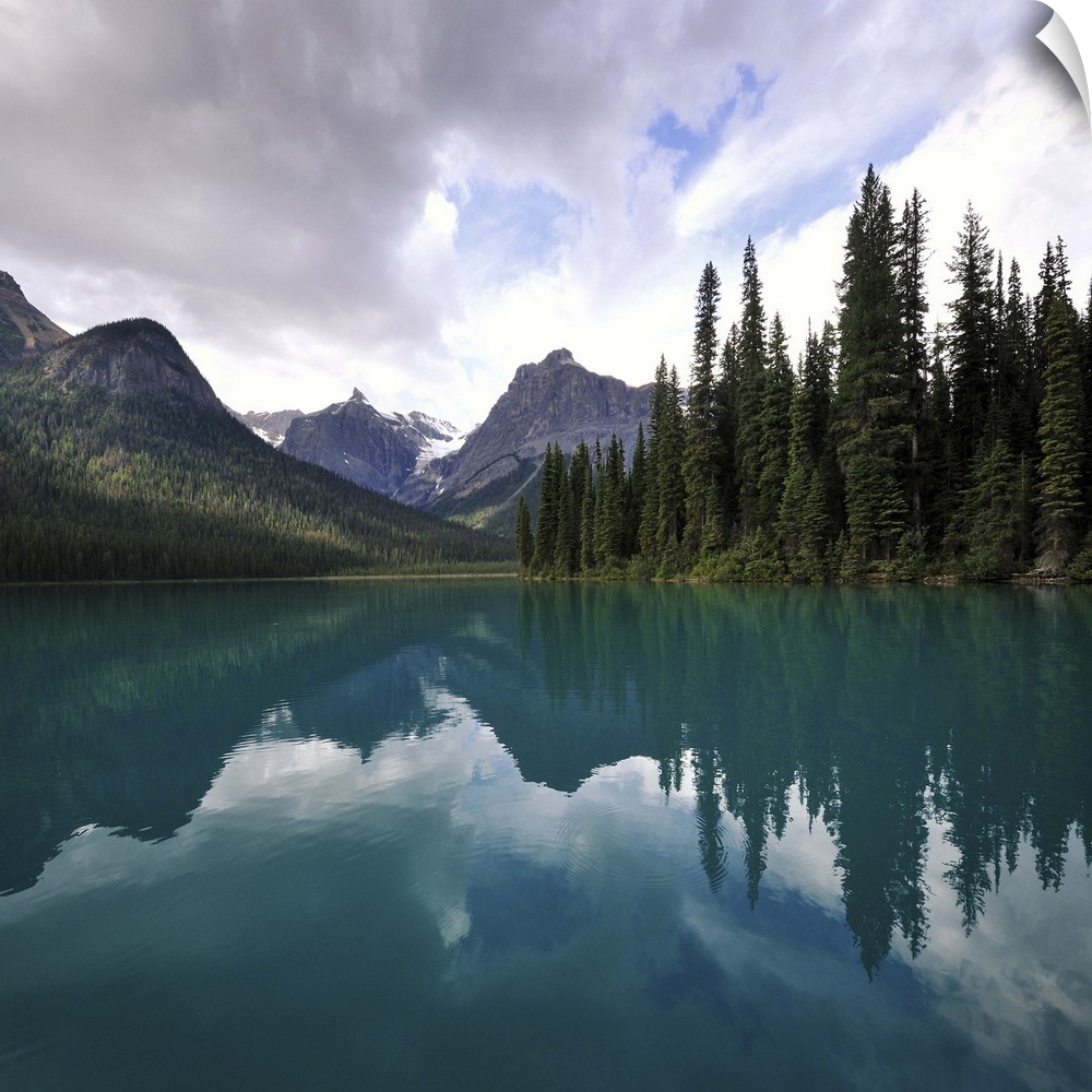 Clouds over mountain and trees with reflection in Emerald lake, Alberta Canada.