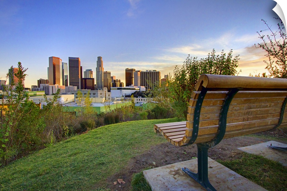 Photograph of park bench overlooking city skyline at dusk.
