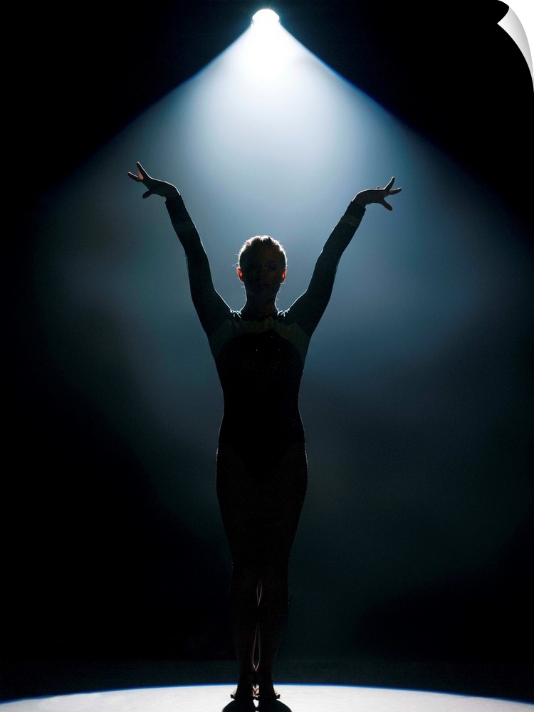 Female gymnast performing in spotlight, studio shot