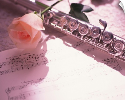 Flute next to sheet music and pink rose