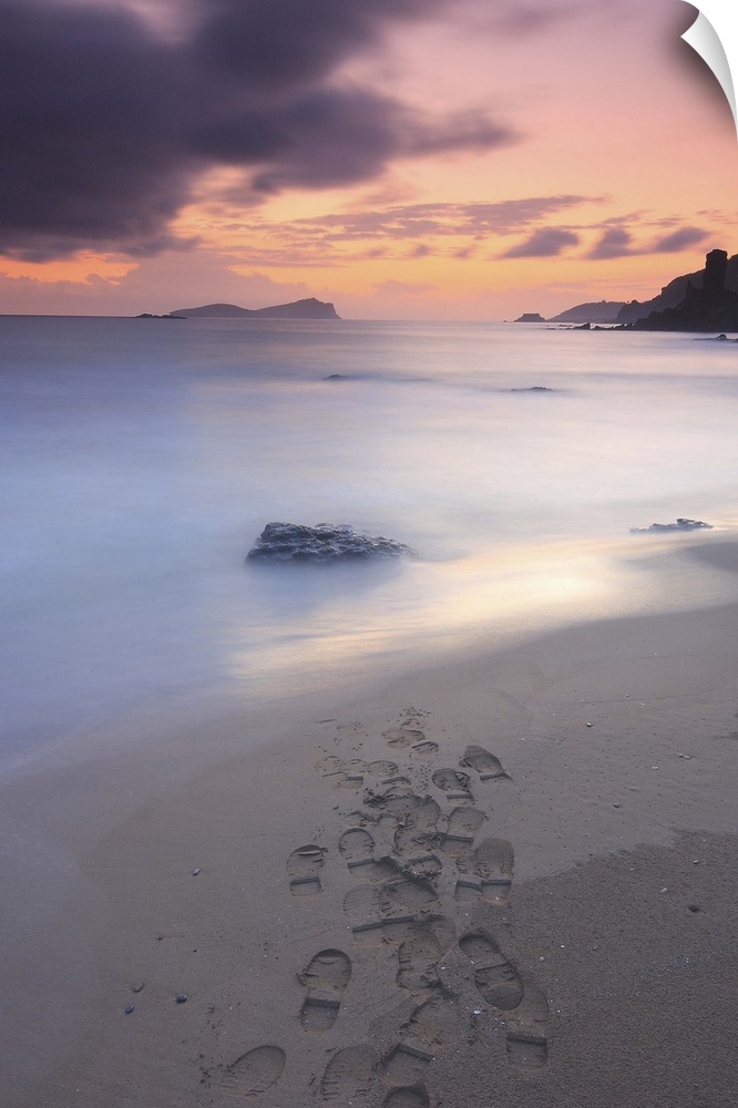 Footprints on beach at sunset.