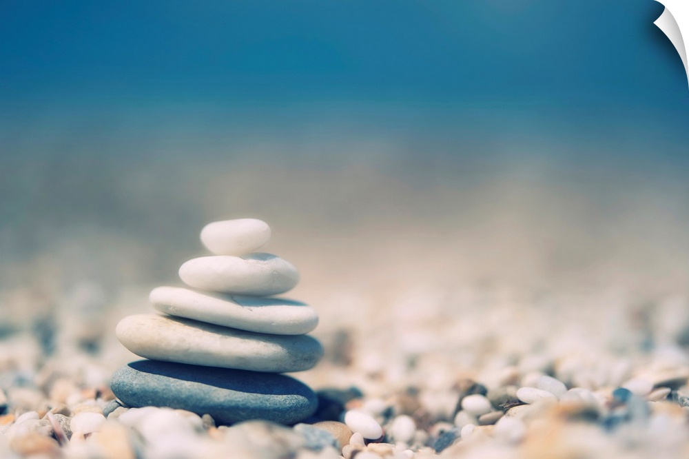 Up-close photograph of stacked smooth stones balancing on a bed of smaller pebbles.