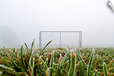 Frost and fog and football goal on soccer field.